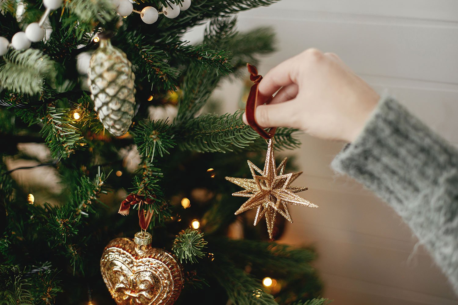 A hand decorating a christmas tree